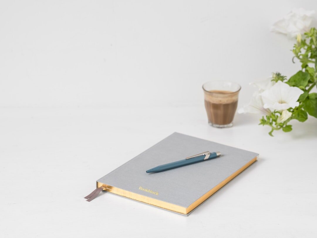 Open notebook with a cup of coffee and a pen on a light desk