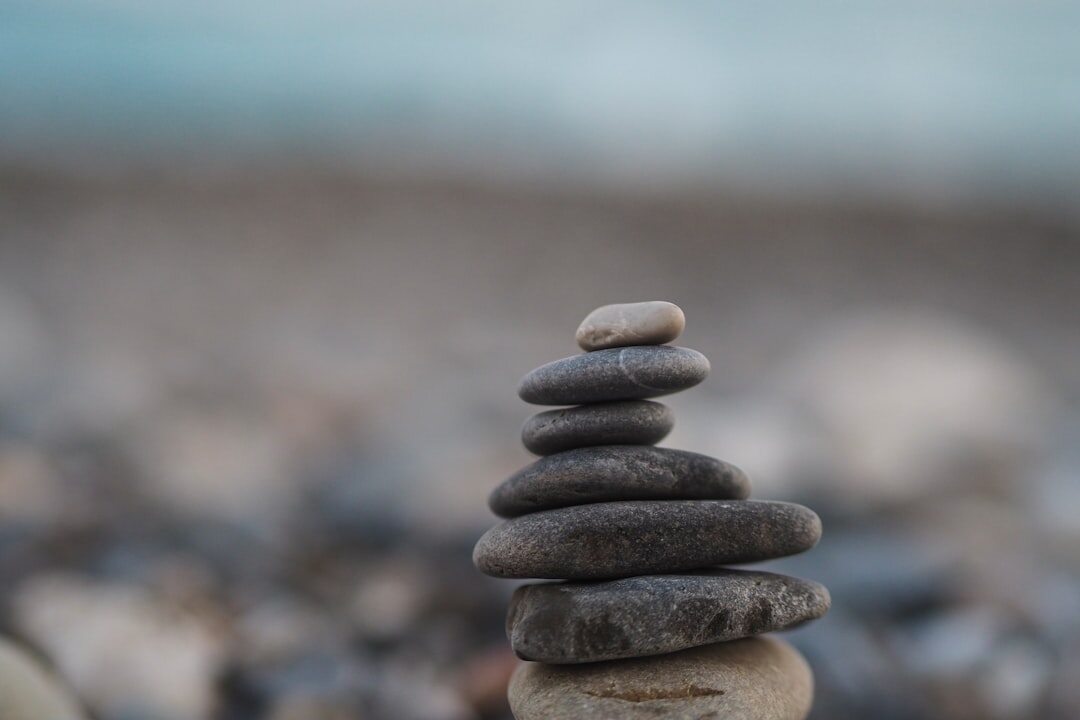 Hands arranging small stones into a balanced stack outdoors